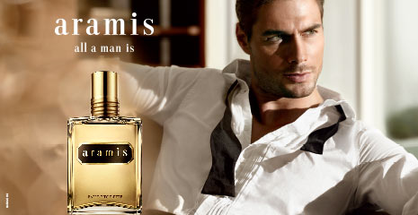 Werbung für Aramis Eau de Toilette. Links im Bild ist der goldene Parfümflakon mit schwarzem Etikett zu sehen. Rechts lehnt ein attraktiv gekleideter Mann in einem halb geöffneten weißen Hemd lässig zurück. Text auf dem Bild: 'aramis – all a man is'.