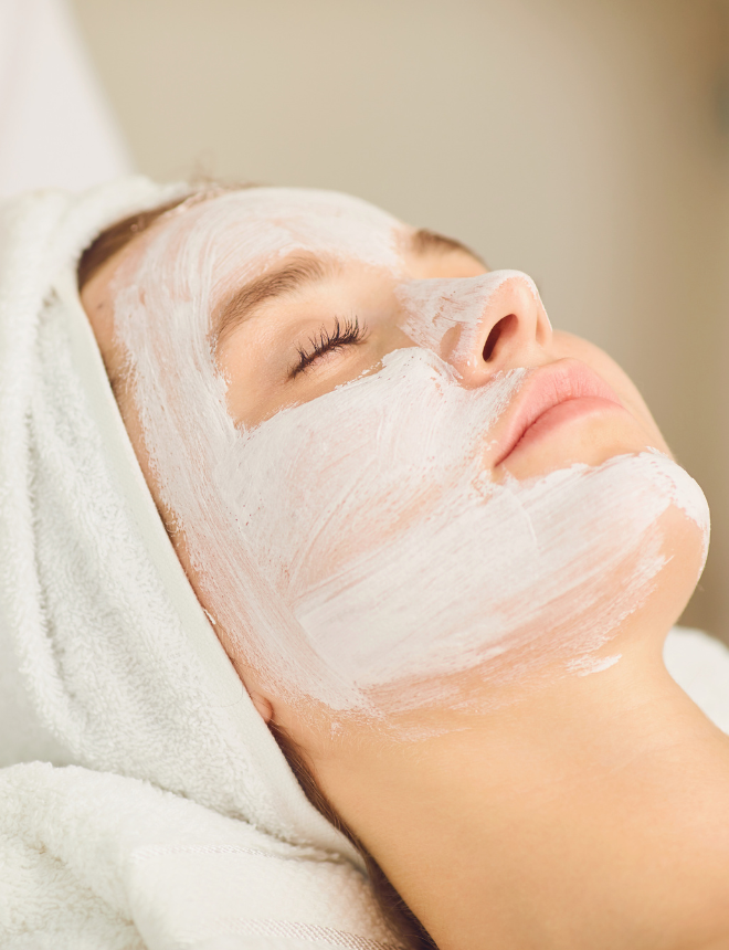 Entspannte Frau mit weißer Gesichtsmaske und Handtuch im Haar, Artikelbild Naturkosmetik