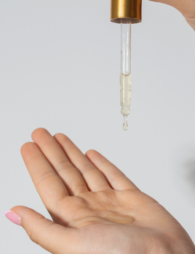 Pipette mit goldenem Serum tropft in eine geöffnete Hand, Artikelbild Naturkosmetik