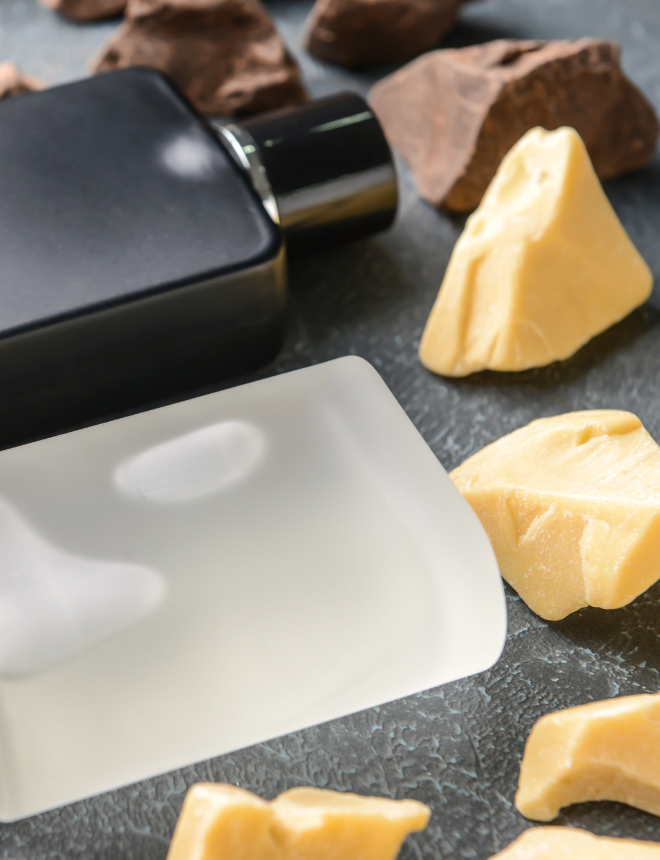 Mattschwarzer Parfümflakon zwischen Kakaobohnen und Kakaobutter, Herbstdüfte gourmand
