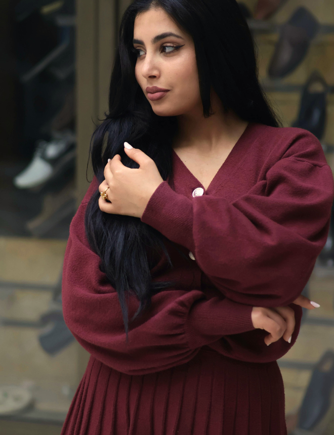 Frau mit dezentem Make-up und langen dunklen Haaren in bordeauxrotem Outfit