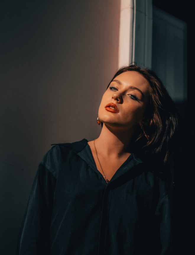 Frau mit rotem Lippenstift und dunklem Blazer im dramatischen Lichteinfall