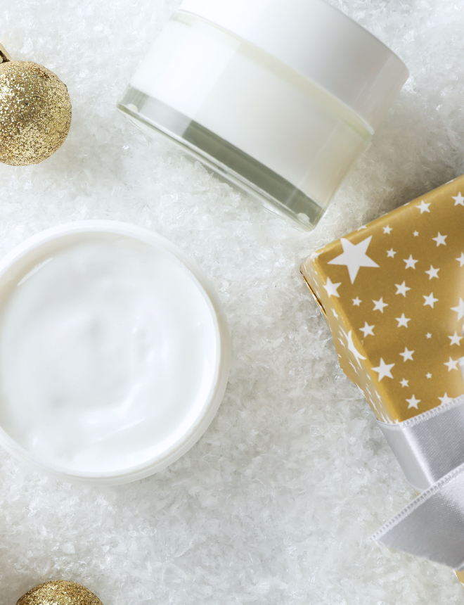 Pflegecremes und Geschenk mit Sternmotiv auf Kunstschnee, weihnachtlich dekoriert