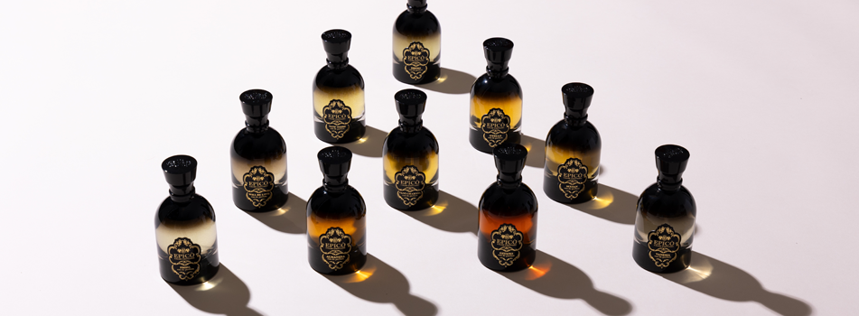 Epicò Artistic Perfume – Zehn schwarze Parfümflakons mit goldfarbenen Etiketten im Diamant-Muster auf hellem Hintergrund mit langen Schatten