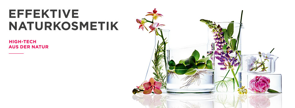 Annemarie Börlind Naturkosmetik Arrangement aus Laborgefäßen mit verschiedenen frischen Pflanzen und Blüten, symbolisierend die Verbindung von Natur und Wissenschaft in effektiver Naturkosmetik. Links daneben der Text ‚Effektive Naturkosmetik – High-Tech aus der Natur‘