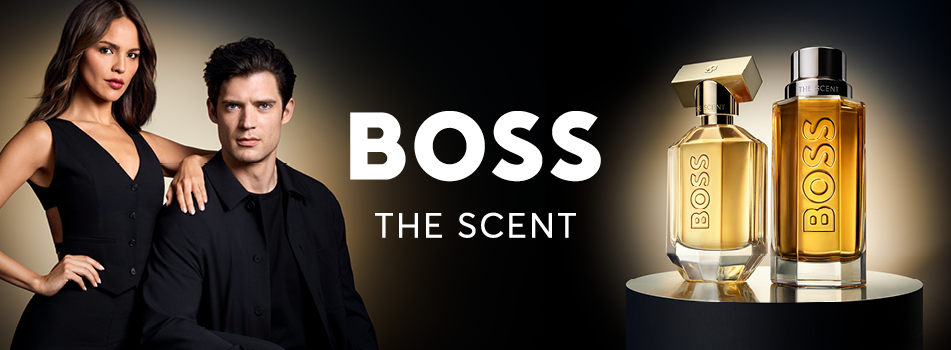 Eine Frau in elegantem schwarzem Kleid steht neben einem Mann in dunklem Anzug, beide blicken selbstbewusst in die Kamera. Rechts daneben die goldfarbenen Flakons des Dufts „BOSS The Scent“ vor schwarzem Hintergrund – Sinnlichkeit und Eleganz im Fokus.