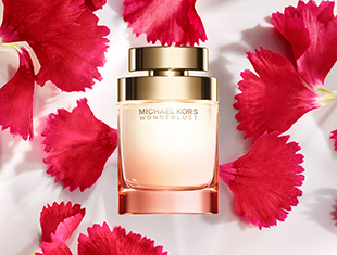 Parfumflakon von 'Michael Kors Wonderlust' in einem zarten Roséton mit goldener Kappe. Der Flakon steht inmitten von leuchtend pinken Blütenblättern auf weißem Hintergrund.