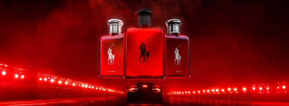 Werbung für ein Parfum von Ralph Lauren: Drei leuchtend rote Parfumflakons mit dem ikonischen Polo-Reiter-Logo schweben über einem Sportwagen, der auf einer Straße mit roten Lichtern fährt. Die Szene ist dramatisch in Rot und Schwarz gehalten und vermittelt Dynamik und Luxus.