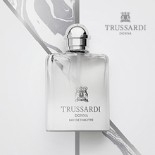 Weiß-silberner Parfumflakon 'Trussardi Donna Eau de Toilette' mit glänzendem Verschluss vor hellem, marmoriertem Hintergrund. Rechts oben steht das Trussardi-Logo mit dem Schriftzug 'Trussardi Donna'.